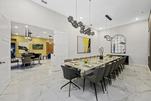 Un comedor moderno con una mesa larga, sillas e iluminación decorativa.