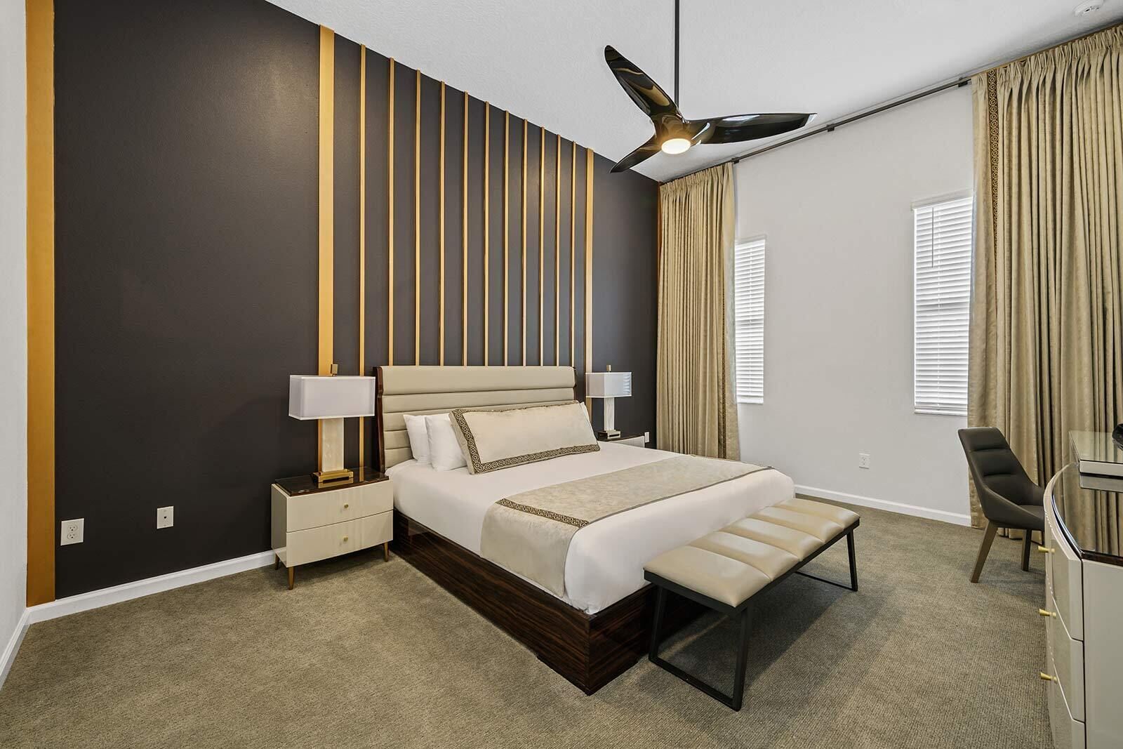 A modern hotel room with a large bed, bedside tables, a desk, and a ceiling fan.
