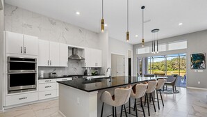 Cocina moderna con armarios blancos, encimera negra y una isla central con taburetes de bar.