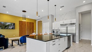 Una cocina moderna con una isla central, muebles blancos y electrodomésticos de acero inoxidable.