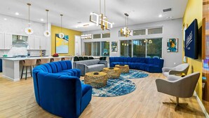 A modern living room with a blue sectional sofa, a round coffee table, and a TV on the wall.