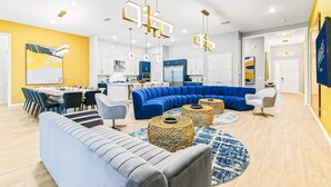 A modern living room with a blue sectional sofa, a grey sofa, and a dining area with a table and chairs. - Elegant Home w/ Ice Themed BR, Bowling, Karaoke RM, Theater & Gym - Near Parks (Davenport)