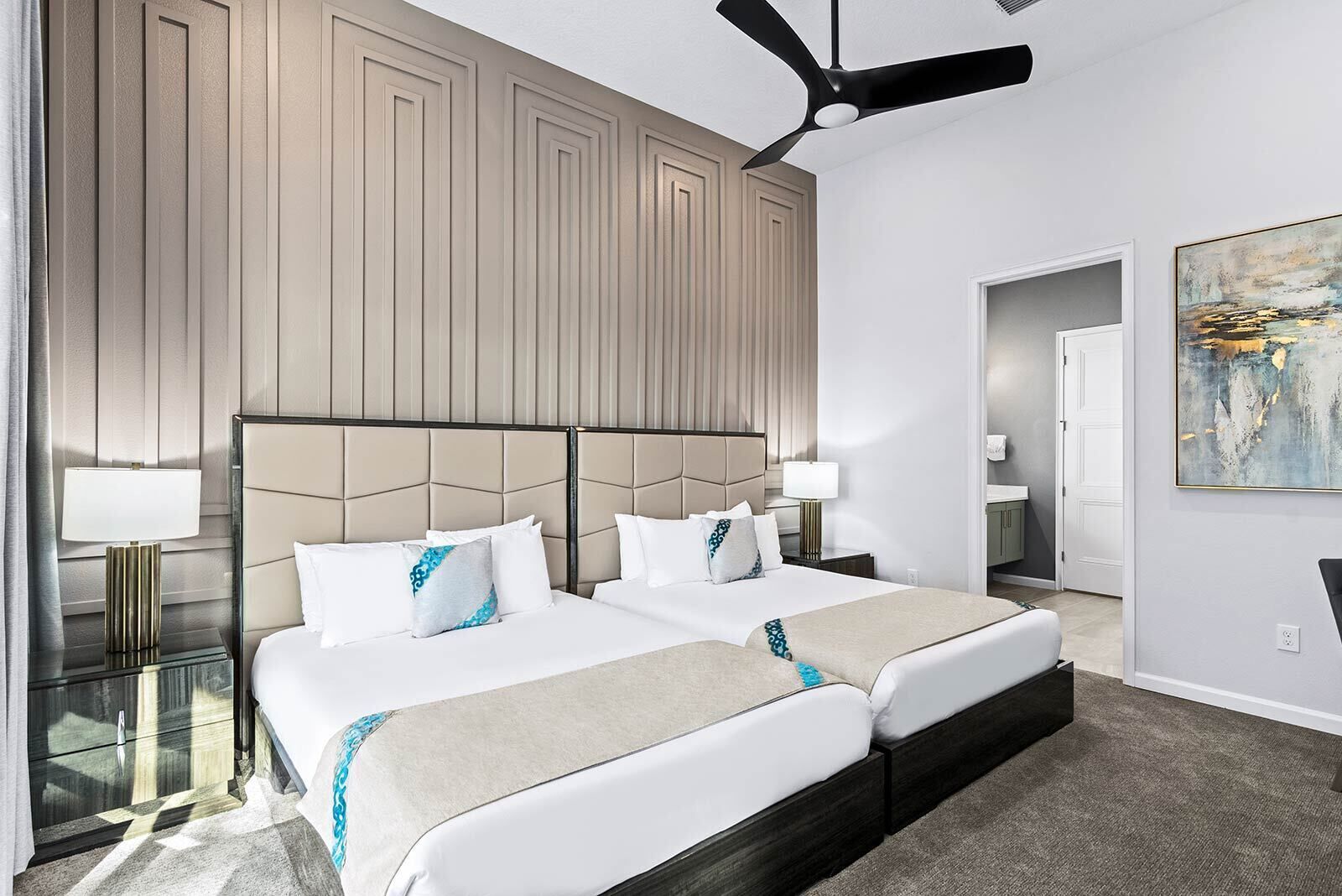 Habitación de hotel con una cama grande, dos mesitas de noche, un ventilador de techo y un cuadro en la pared.