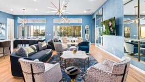 A spacious living area with a large sofa, armchairs, and a coffee table. There are multiple seating options and a dining area with a table and chairs. - Homes by Villatel | Music Studio, Bowling, Pirate BR, Theater & Gym, Near Disney (Davenport)