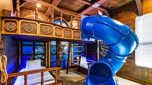 A multi-level wooden cabin with a blue slide. - Homes by Villatel | Music Studio, Bowling, Pirate BR, Theater & Gym, Near Disney (Davenport)