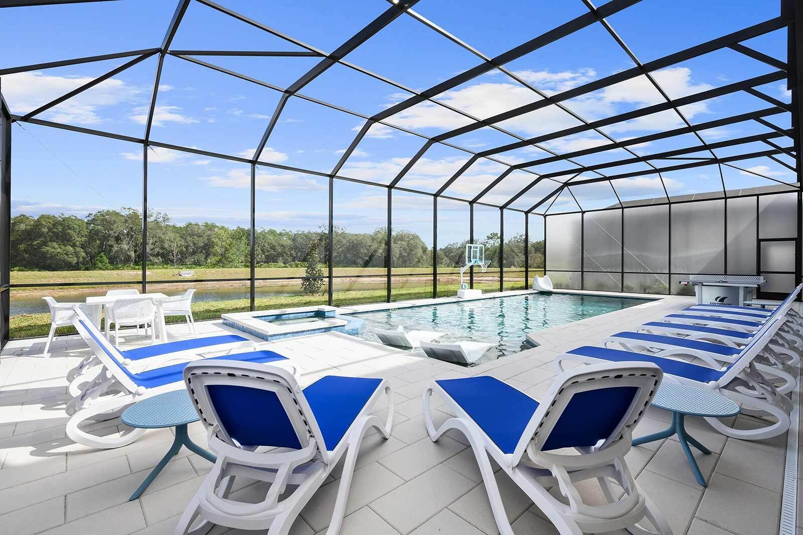 A covered outdoor swimming pool with lounge chairs and a basketball hoop.