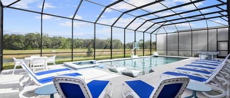 A covered outdoor swimming pool with lounge chairs and a basketball hoop.