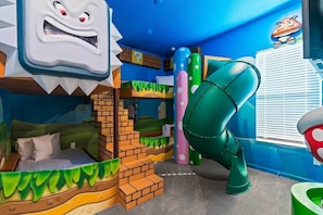 A children's play area with a slide, bunk beds, and a cartoon character mural. - Eye Candy Home w Lollipop BR, Ninja Playroom, Theater, Arcade, Gym, Near Disney (Davenport)