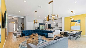 A modern living room with a sectional sofa, a coffee table, and a dining area with a table and chairs.