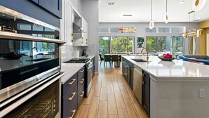 A modern kitchen with a large island, stainless steel appliances, and a view of the outdoors.