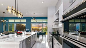 A modern kitchen with a large island, stainless steel appliances, and a view of the outdoors.