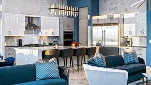 A modern kitchen with marble countertops, stainless steel appliances, and a central island with bar stools.