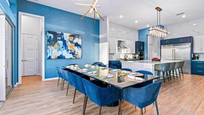 A modern kitchen with white cabinets, a stainless steel refrigerator, and a blue accent wall. - Super Villa Near Disney w Sci-Fi Arcade, Space Theme BR, Theater, Gym, Spa Pool (Davenport)