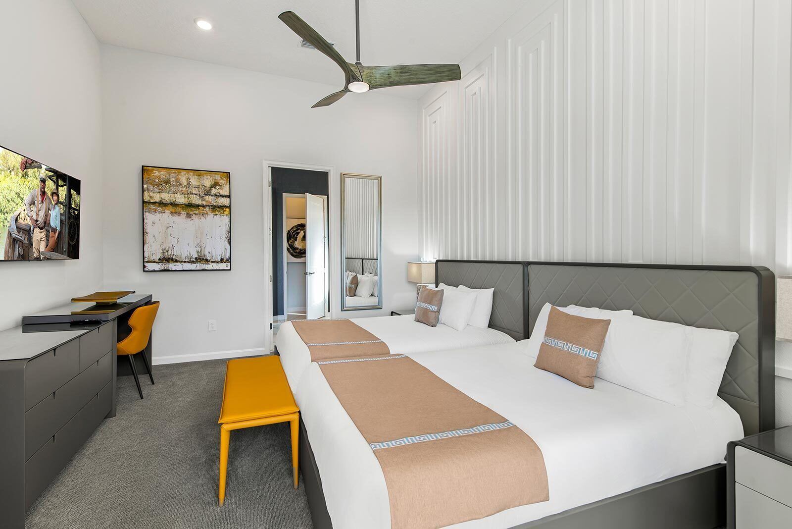 Habitación de hotel con cama, escritorio, silla y ventilador de techo.