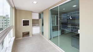 A modern apartment with a balcony, a kitchenette, and a glass door leading to a living area.