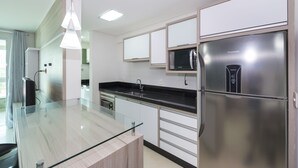 A modern kitchen with a stainless steel refrigerator, a microwave, and a glass island counter.