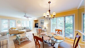 A spacious living room with a round glass table, beige sofas, and a ceiling fan. - Beautifully Updated One Bedroom Villa Great for a Couples Getaway! (Hilton Head)