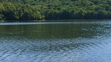 A small boat on a calm lake with a forested hill in the background.