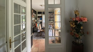 Een gang met een witte deur die leidt naar een bibliotheek vol boekenplanken.