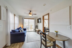 Ein Wohnzimmer mit blauem Sofa, Esstisch aus Holz und Deckenventilator.