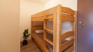 A bunk bed in a room with a door and a potted plant.
