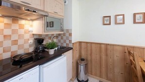 A kitchen with wooden cabinets, a black countertop, a white dishwasher, and a stainless steel trash can.