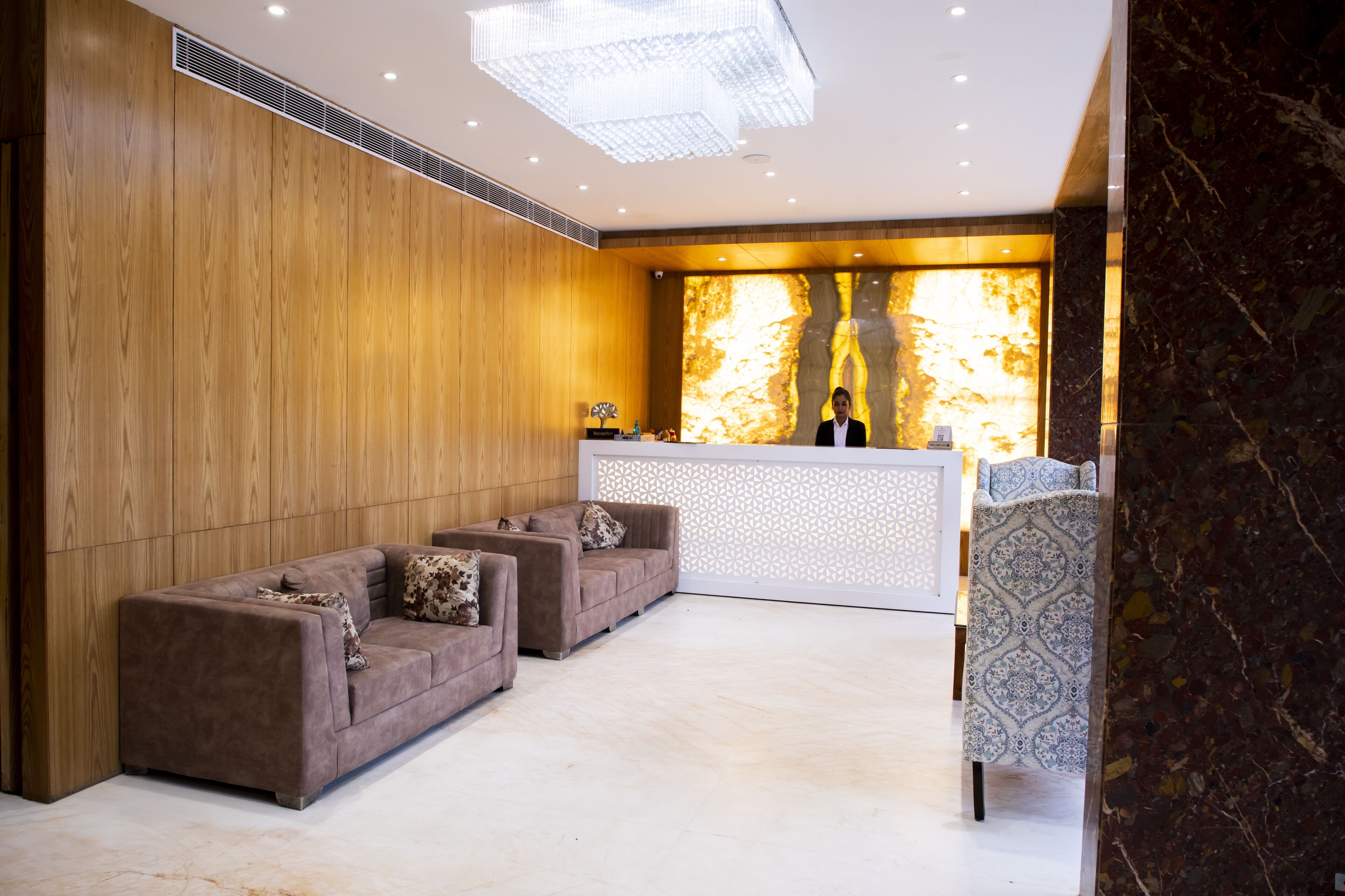 A reception area with a wooden wall, a reception desk, and two sofas.