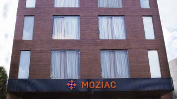Un edificio moderno con un letrero que dice "MOZIAC" y una escalera que lleva a la entrada.
