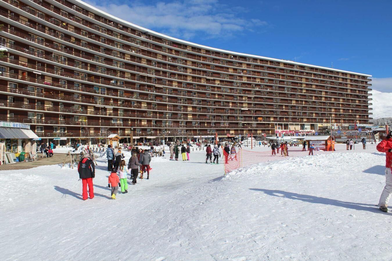 Un grand hôtel à plusieurs étages, doté de nombreux balcons, avec une station de ski en premier plan.