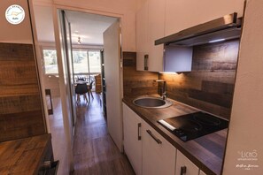 A modern kitchen with wooden cabinetry, a built-in oven, and a window overlooking a dining area.