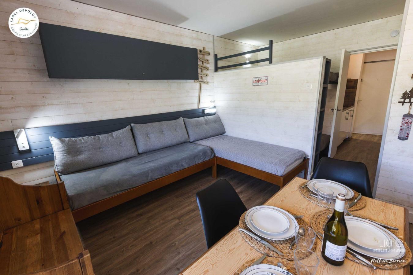 A compact living space with a sofa, a dining table set for two, and a small kitchen area.