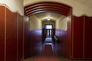 Un pasillo con alfombra roja, paredes de madera con adornos decorativos y una puerta al final.