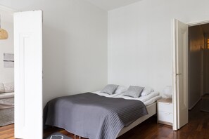 A bedroom with a bed, bedside table, and a door leading to another room. - 2ndhomes Cozy & Spacious 2BR Apartment (Helsinki)
