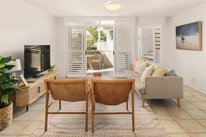 A modern living room with a TV, sofa, and dining area. - Spacious Seaside Oasis on Dicky Beach (Dicky Beach)