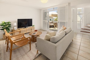 A living room with a sofa, TV, and a dining area with a table and chairs.