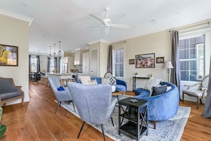 A spacious living area with a dining area, a kitchen, and a ceiling fan.