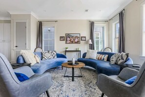 A living room with a blue sofa set, a round coffee table, and a patterned rug.