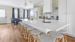 Une cuisine moderne dotée d’un grand îlot central, de tabourets de bar et d’un coin repas avec une table et des chaises.