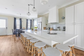 A modern kitchen with a large island, bar stools, and a dining area with a table and chairs.