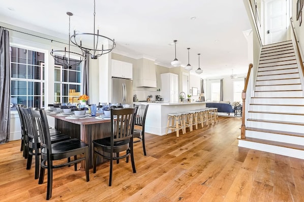 A spacious kitchen with a central island, wooden flooring, and pendant lighting.