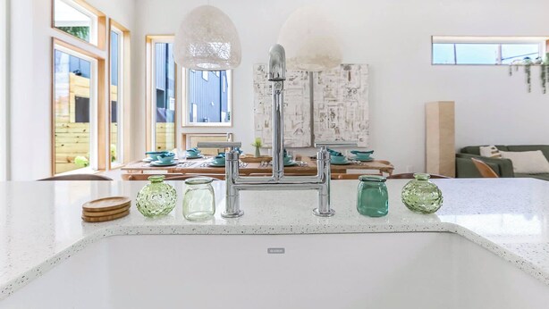 A kitchen with a modern faucet, a white countertop, and a view of the dining area. - Paradise | Private Hot Tub + Shared Heated Pool (New Orleans)
