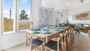 A dining area with a long wooden table set for six, wooden chairs, and pendant lights. - Paradise | Private Hot Tub + Shared Heated Pool (New Orleans)