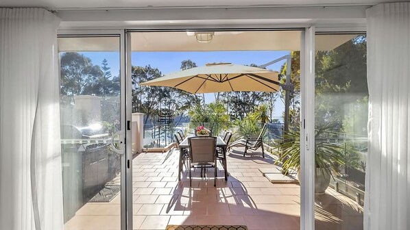 Enjoy a patio with a table, chairs, and umbrella, surrounded by lush greenery and a scenic view.