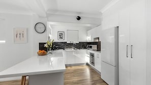 Enjoy cooking in this well-equipped kitchen with a central island, white cabinetry, and stainless steel appliances.