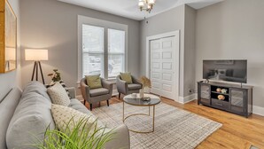 A living room with a gray sofa, two armchairs, a coffee table, a TV stand, and a ceiling fan. - Recently Renovated Home In The Heart Of Bellevue! 2 Bedroom Home by RedAwning (Bellevue)