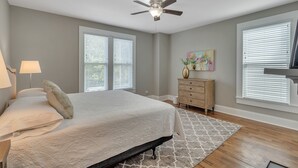 A bedroom with a bed, a ceiling fan, a dresser, and a window with blinds. - Recently Renovated Home In The Heart Of Bellevue! 2 Bedroom Home by RedAwning (Bellevue)