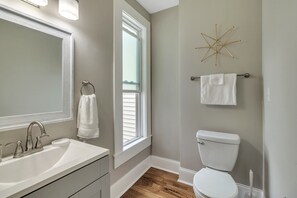 Ein Badezimmer mit einem weißen Waschbecken, einer Toilette und einem Fenster mit Jalousien.
