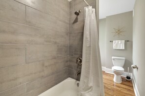 Une salle de bain avec une douche, des toilettes et une baignoire.