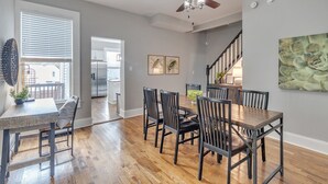 A dining area with a wooden table and chairs, a ceiling fan, and a staircase leading to an upper level. - Recently Renovated Home In The Heart Of Bellevue! 2 Bedroom Home by RedAwning (Bellevue)