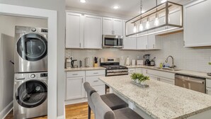 A modern kitchen with stainless steel appliances, white cabinetry, and a granite countertop. - Recently Renovated Home In The Heart Of Bellevue! 2 Bedroom Home by RedAwning (Bellevue)